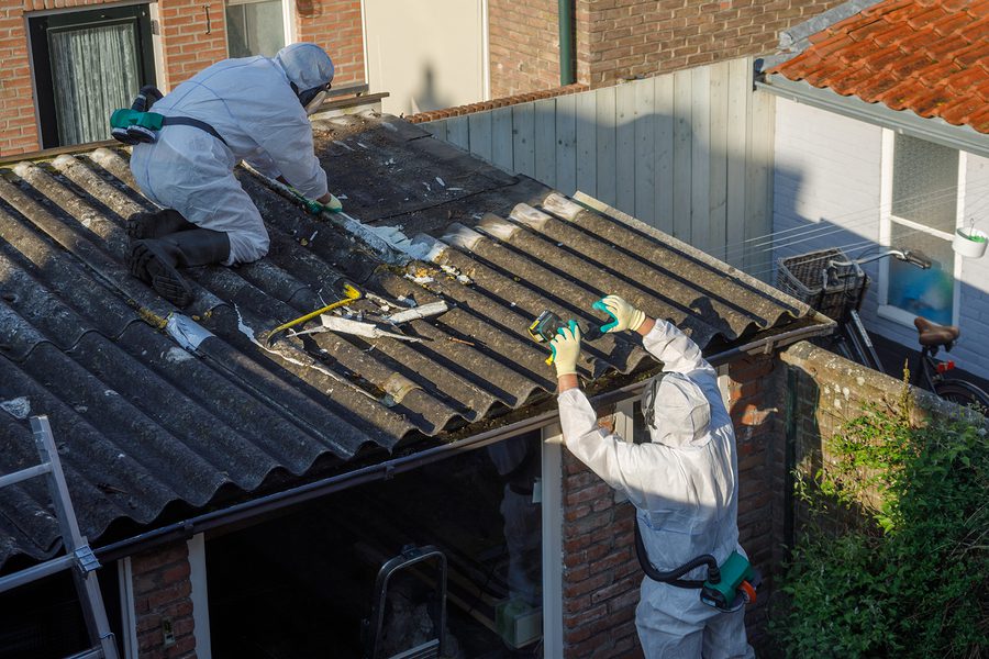 men in protective suit removing asbestos cement